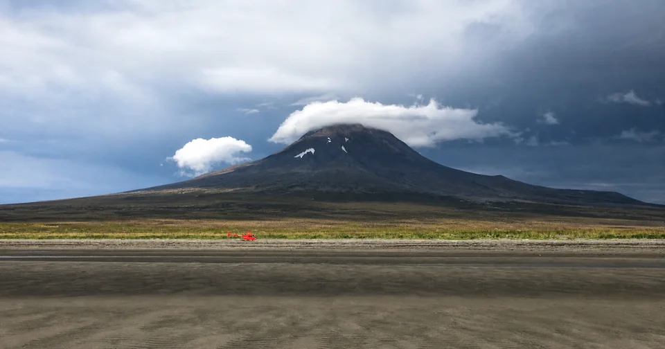 Red helicopter beneath a remote Alaska volcano