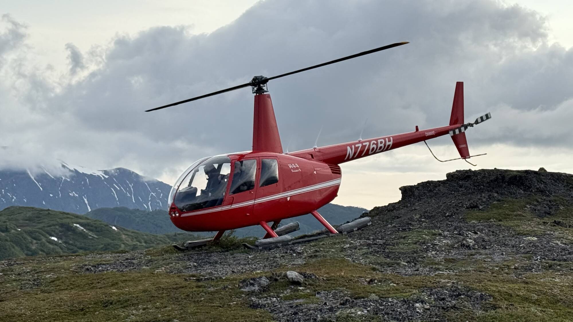 Red helicopter on remote Alaska ridge during a helicopter bear viewing tour