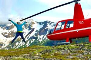 Red helicopter landing in remote Alaska mountains for a helicopter bear viewing tour